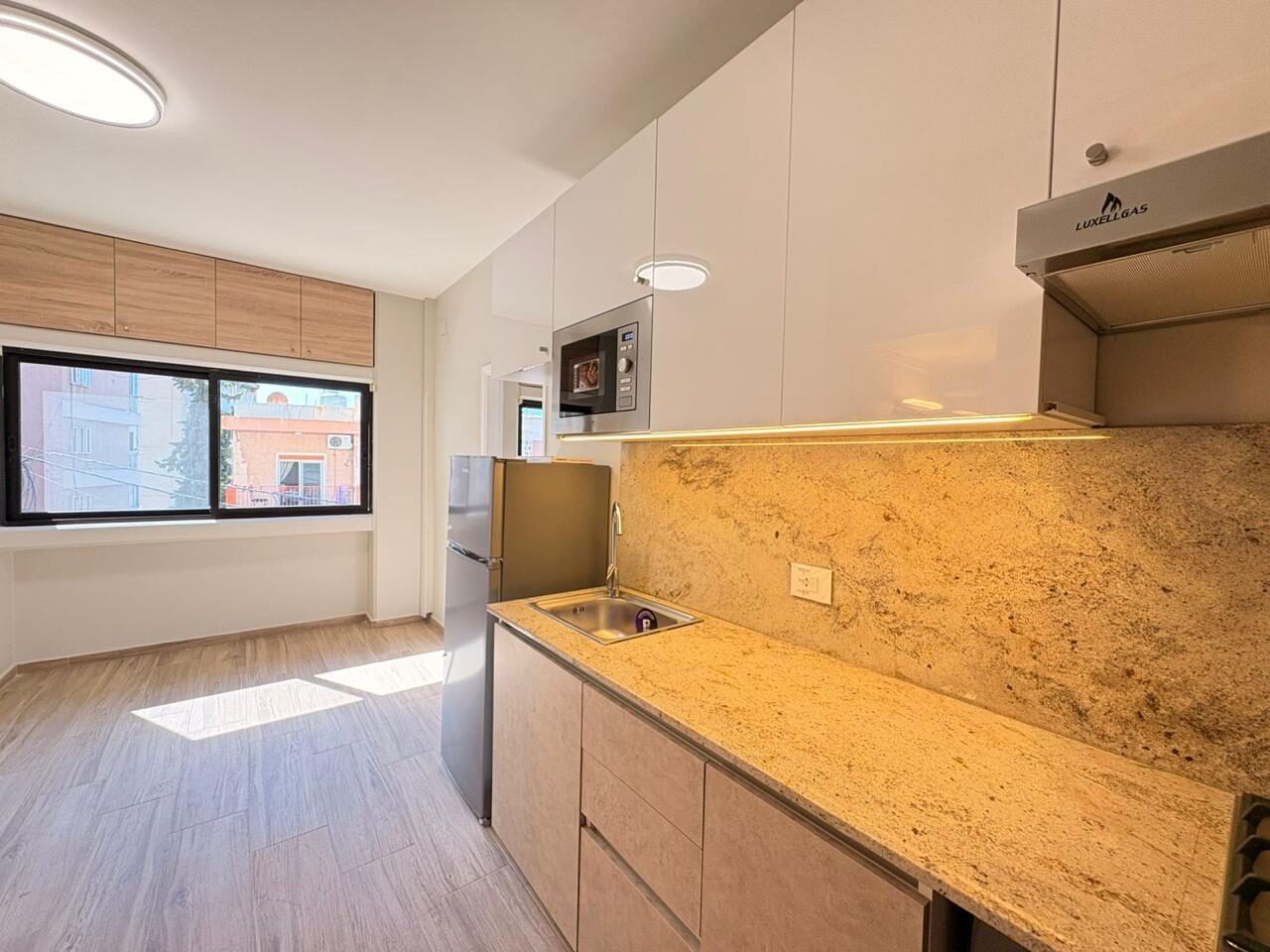 Studio kitchen and living space with a sunlit window