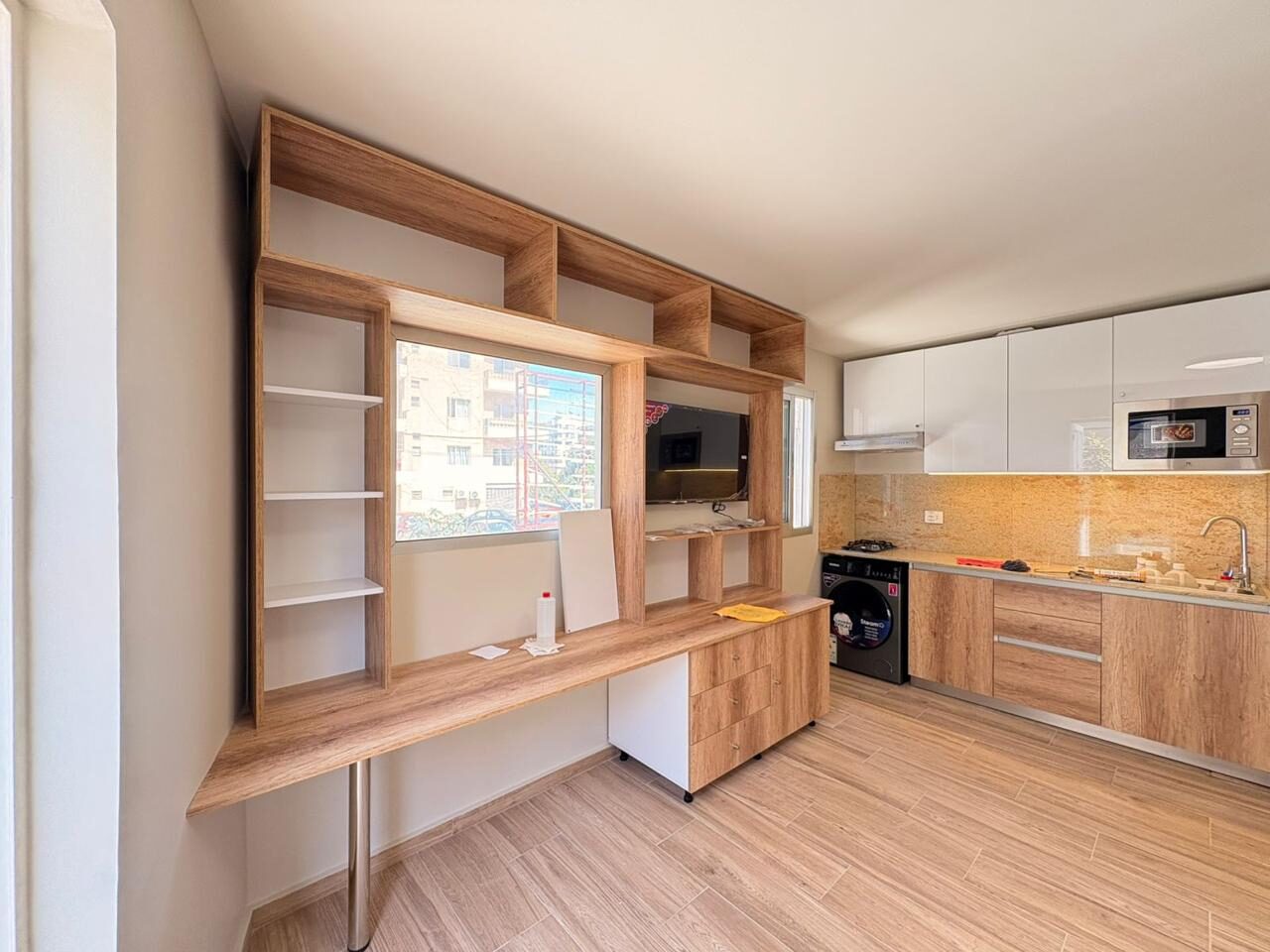 Studio desk wall with shelving and kitchen beyond